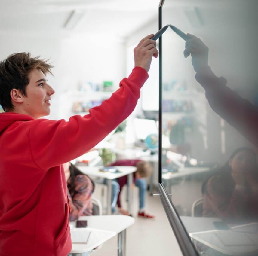 Foto di un giovane studente mentre utilizza uno schermo interattivo in un’aula scolastica.